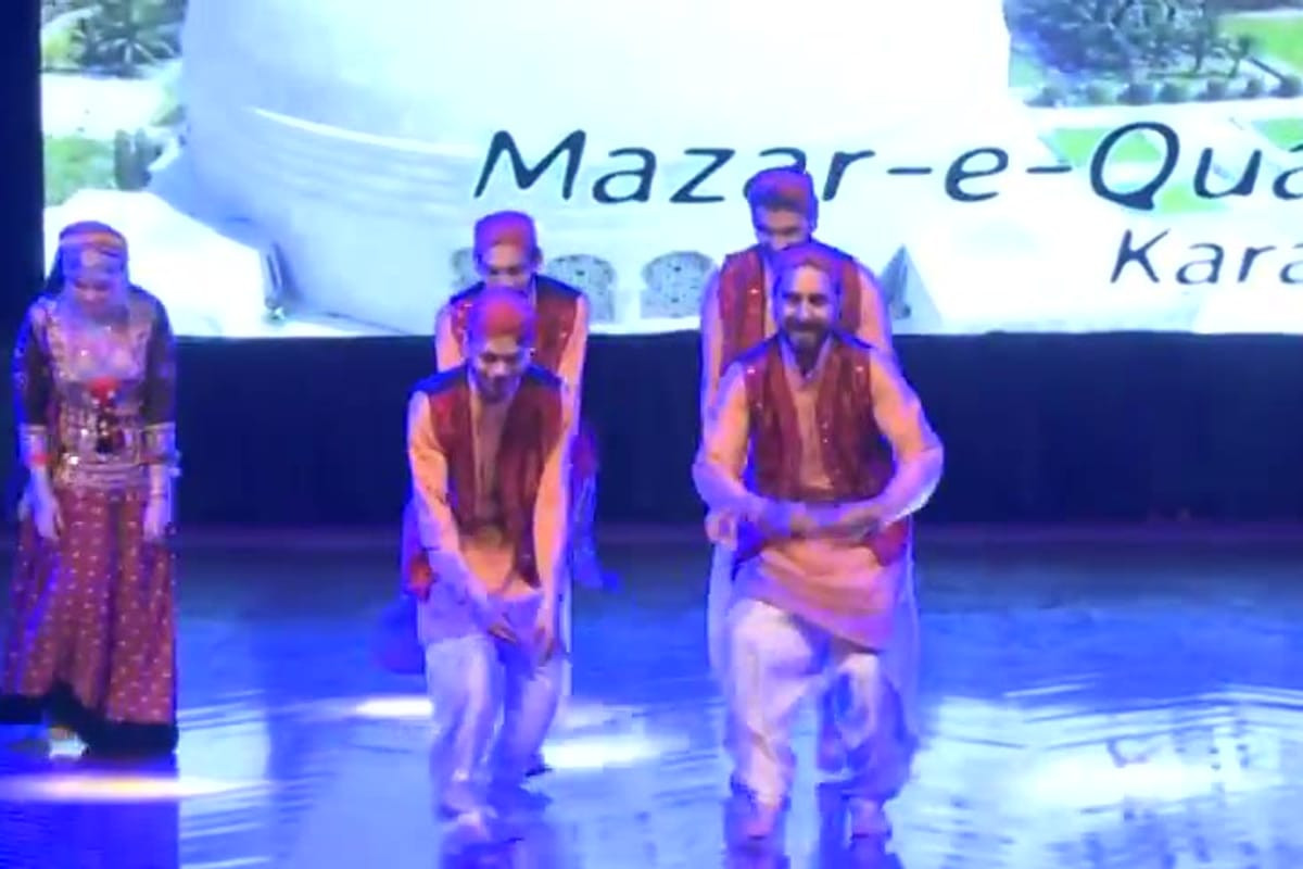 Three VPAG performers mid-movement on a lit stage
